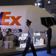 A man dressed as a pilot walks past the FedEx booth during the China International Import Expo in Shanghai on November 5, 2018